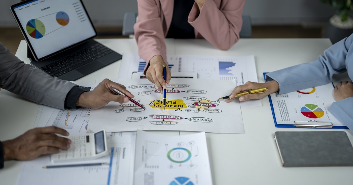 Business team reviewing strategy charts and plans around a table — UK business restructuring