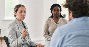 Insights 65 A facilitator leading a calm three-way discussion in a bright room — conciliation and how ACAS works in the UK