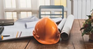 Insights 73 Hard hat resting on architectural blueprints on a wooden desk — the Construction Act 1996 in the UK