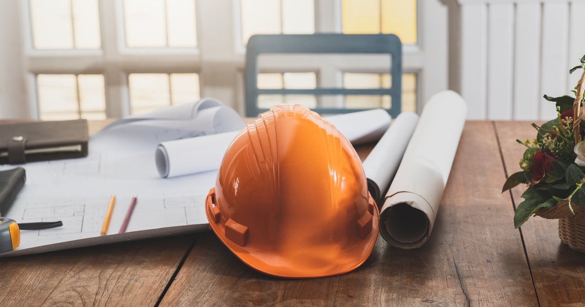 Hard hat resting on architectural blueprints on a wooden desk — the Construction Act 1996 in the UK