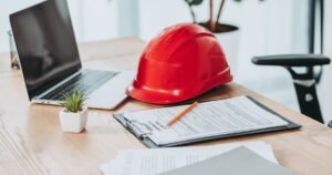 Insights 61 Red hard hat resting on a claim form clipboard beside a laptop on a desk — construction adjudication in the UK
