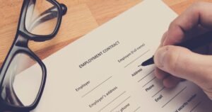 Insights 68 A hand signing an employment contract document with glasses beside it — employment contracts in the UK