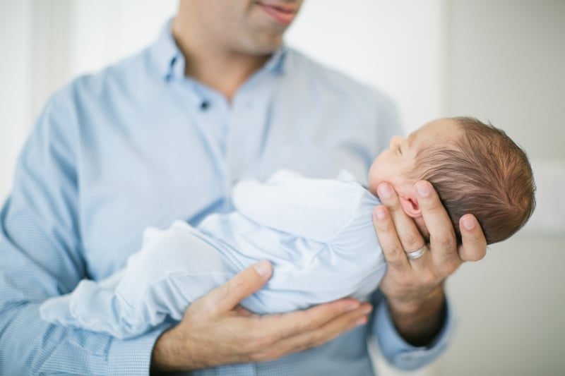 A father on paternity leave holding his newborn baby