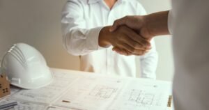 Insights 56 Professionals shaking hands over engineering blueprints and a hard hat — performance bonds in UK construction