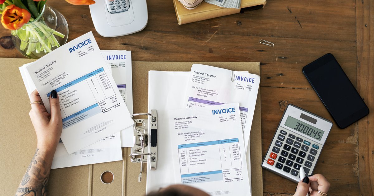 Hands reviewing invoices with a calculator on a desk — reducing your business rates in the UK