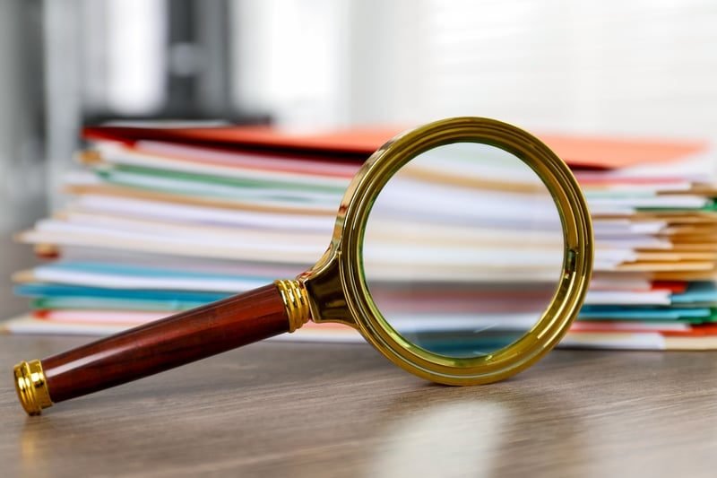 Magnifying glass over documents, representing the Check stage of a rates challenge