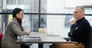 Insights 77 Two professionals in a serious one-to-one meeting across a table — redundancy consultation in the UK