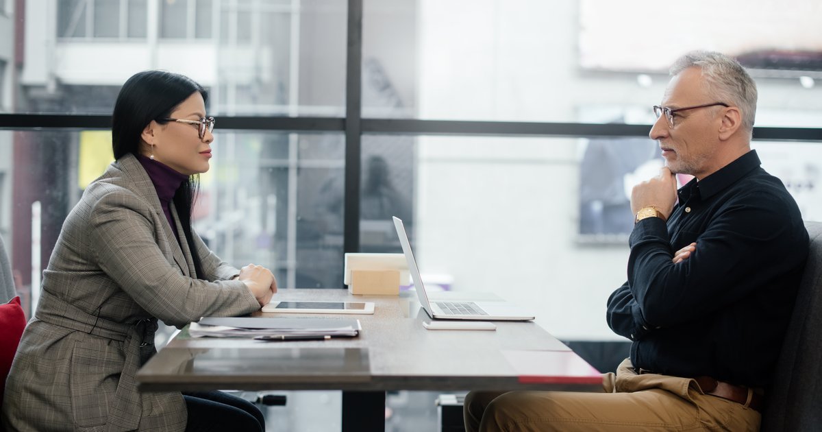 Two professionals in a serious one-to-one meeting across a table — redundancy consultation in the UK