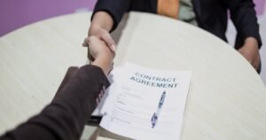 Insights 75 Two parties shaking hands over a signed agreement document on a table — settlement agreements in the UK
