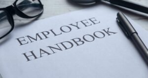 Insights 59 Close-up of an employee handbook on a desk with glasses and pen — UK staff handbooks