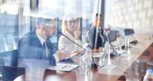 Shareholders in a boardroom meeting around a glass table in a bright office — tag-along rights for London businesses