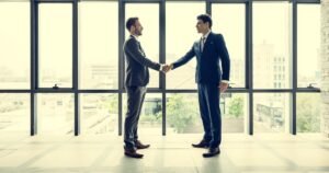 Insights 68 Two business professionals shaking hands in a bright modern office — TUPE transfers and business handovers in the UK