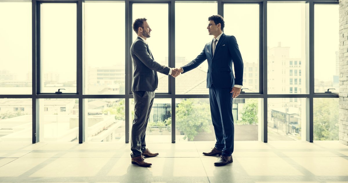 Two business professionals shaking hands in a bright modern office — TUPE transfers and business handovers in the UK
