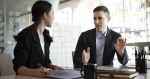 Insights 65 Two professionals having a discussion across a desk in a bright office — without prejudice discussions in the UK